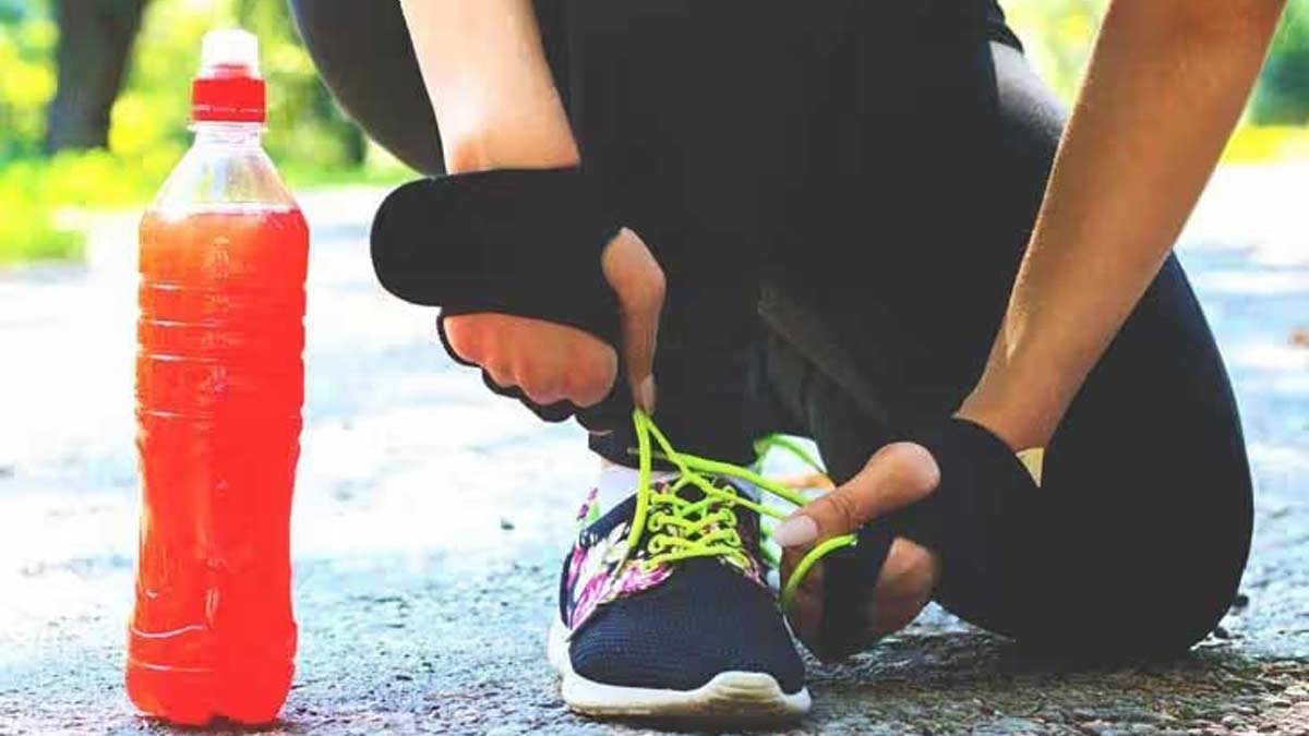 اگر روزانه نوشابه انرژی زا بخوریم چه اتفاقی برای بدن‌ مان می افتد؟- مرد نشسته و در حال بستن بند کفش ورزشی خود است.یک بطری نوشیدنی در کنار آن قرار دارد